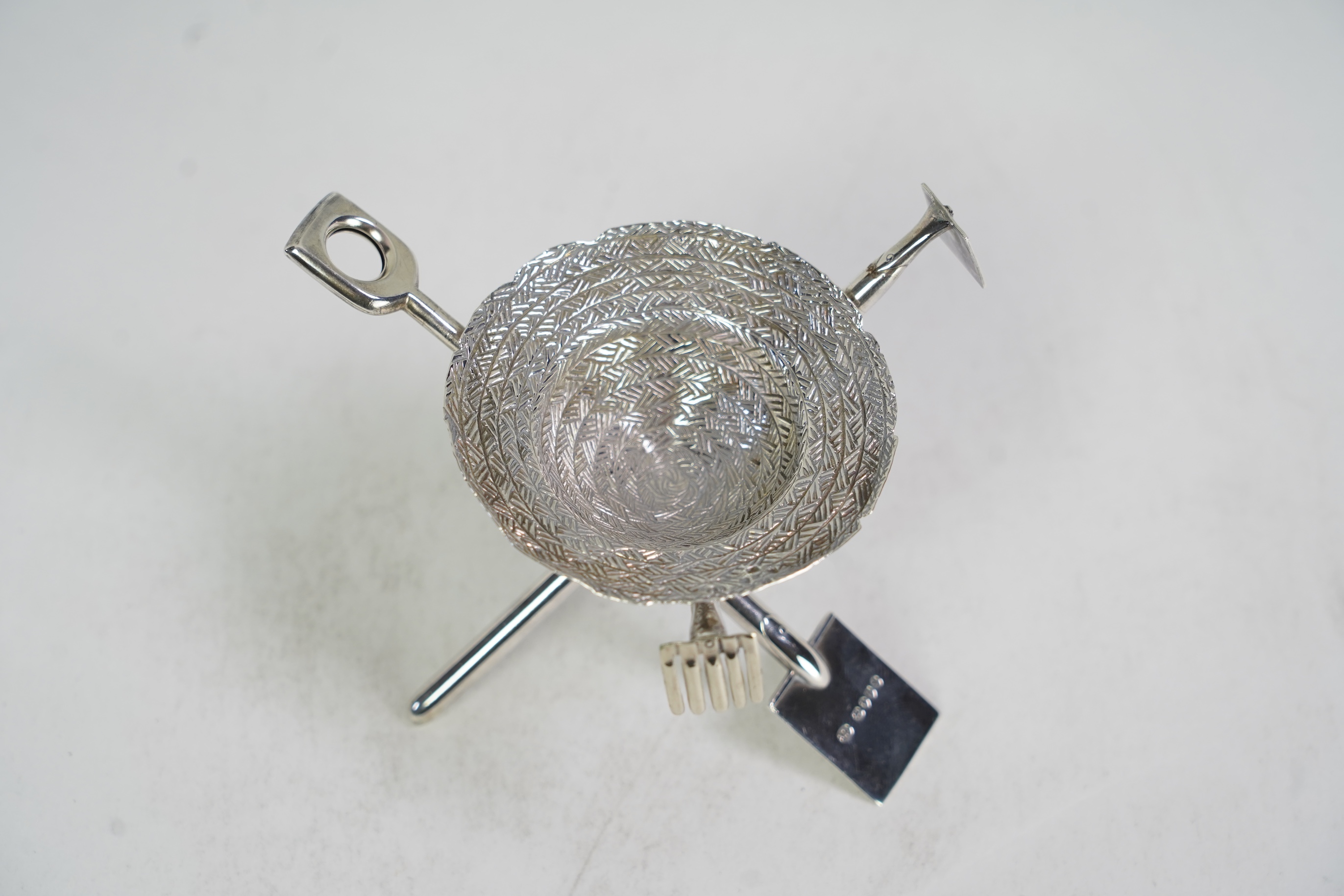 A rare Victorian novelty silver smoker's compendium set, modelled as an upturned straw hat with gardening tools tripod support, by Jane Brownett